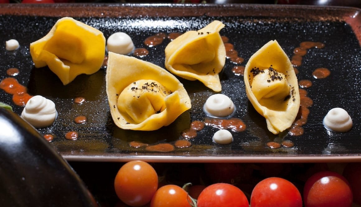 Tortello con farcia di Baccalà di Norvegia e patata, olive, pomodoro e salsa di ricotta di capra