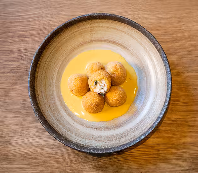 Polpette fritte di stoccafisso norvegese mantecato su salsa di curry.