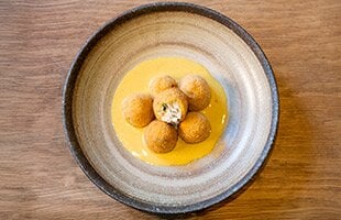 Polpette fritte di stoccafisso norvegese mantecato su salsa di curry.