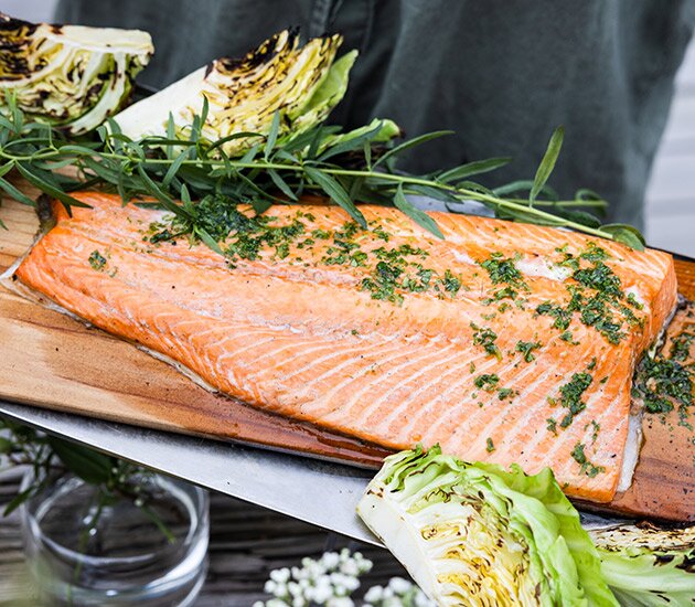 Salmone alla griglia su una tavola con olio alle erbe, patate e cavolo cappuccio grigliato