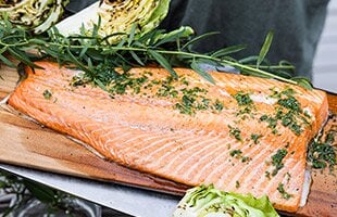 Salmone alla griglia su una tavola con olio alle erbe, patate e cavolo cappuccio grigliato